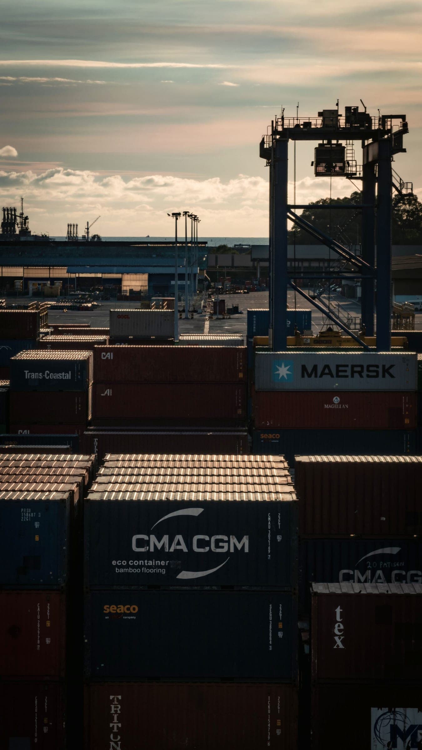 Shipping containers stacked at a port at dusk