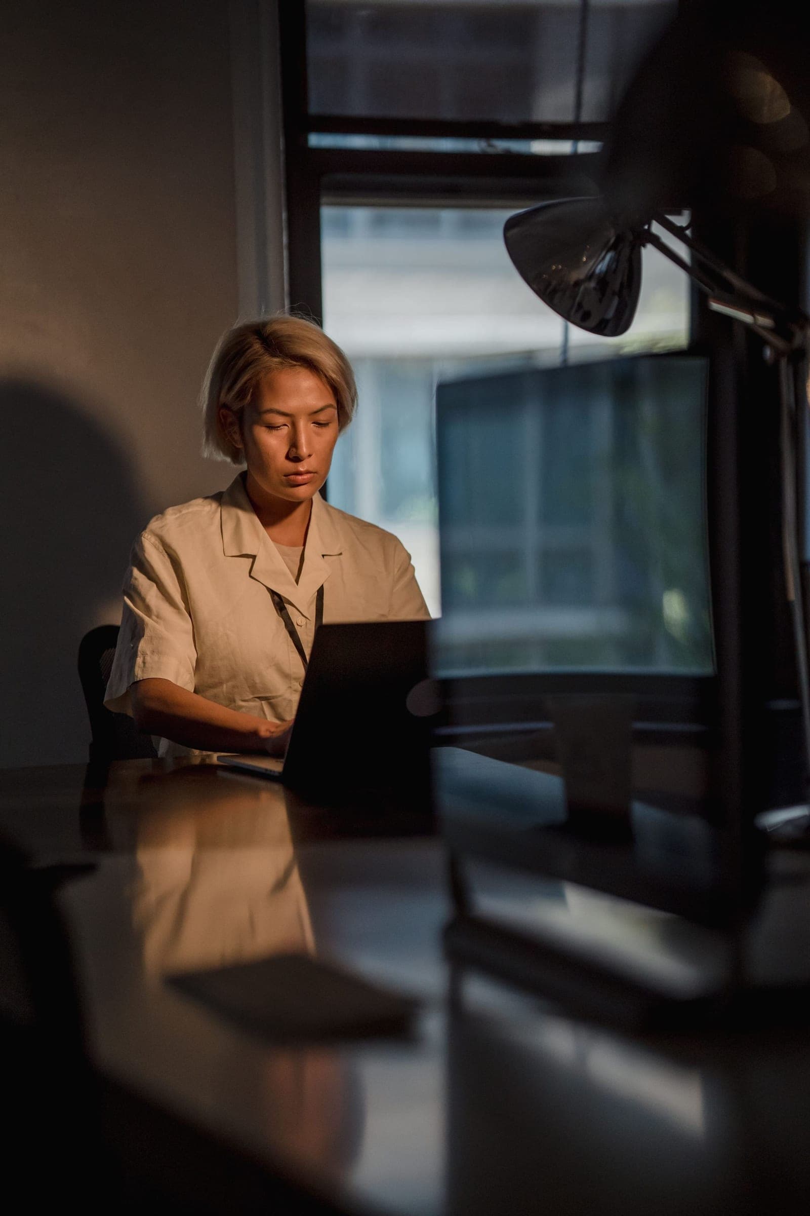 A finance lead working late at a laptop by the window